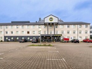 A B&B hotel with a central entrance, multiple parking spaces, and a paved driveway. - B B Hotel Bremen Sud (Bremen)
