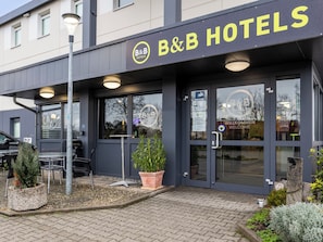 A B&B hotel entrance with a dark facade, glass doors, and a welcome sign. - Ibis Budget Bremen City Sud (Bremen)