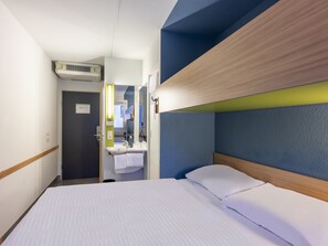 A hotel room with a bed, a bathroom with a sink, and a mirror.