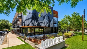 Un edificio moderno con fachada geométrica, mesas al aire libre y un letrero que dice 'TORADOR'.