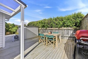 A covered outdoor deck with a table and chairs, a barbecue grill, and a solar panel. - Lime Tree Cottage - Mt Roskill (Mt Roskill)