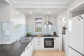 A modern kitchen with a stainless steel sink, a built-in oven, and a refrigerator. - Lime Tree Cottage - Mt Roskill (Mt Roskill)