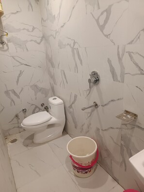 A bathroom with a toilet, a sink, and a decorative bucket on the floor.
