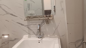 Un baño con un lavabo blanco, un espejo con diseño de cuadrícula y paredes con estampado de mármol.