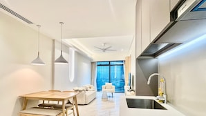 A modern kitchen with a built-in oven, a sink, and a dining area with a wooden table and chairs. - Eaton Residences by ubook (Kuala Lumpur)