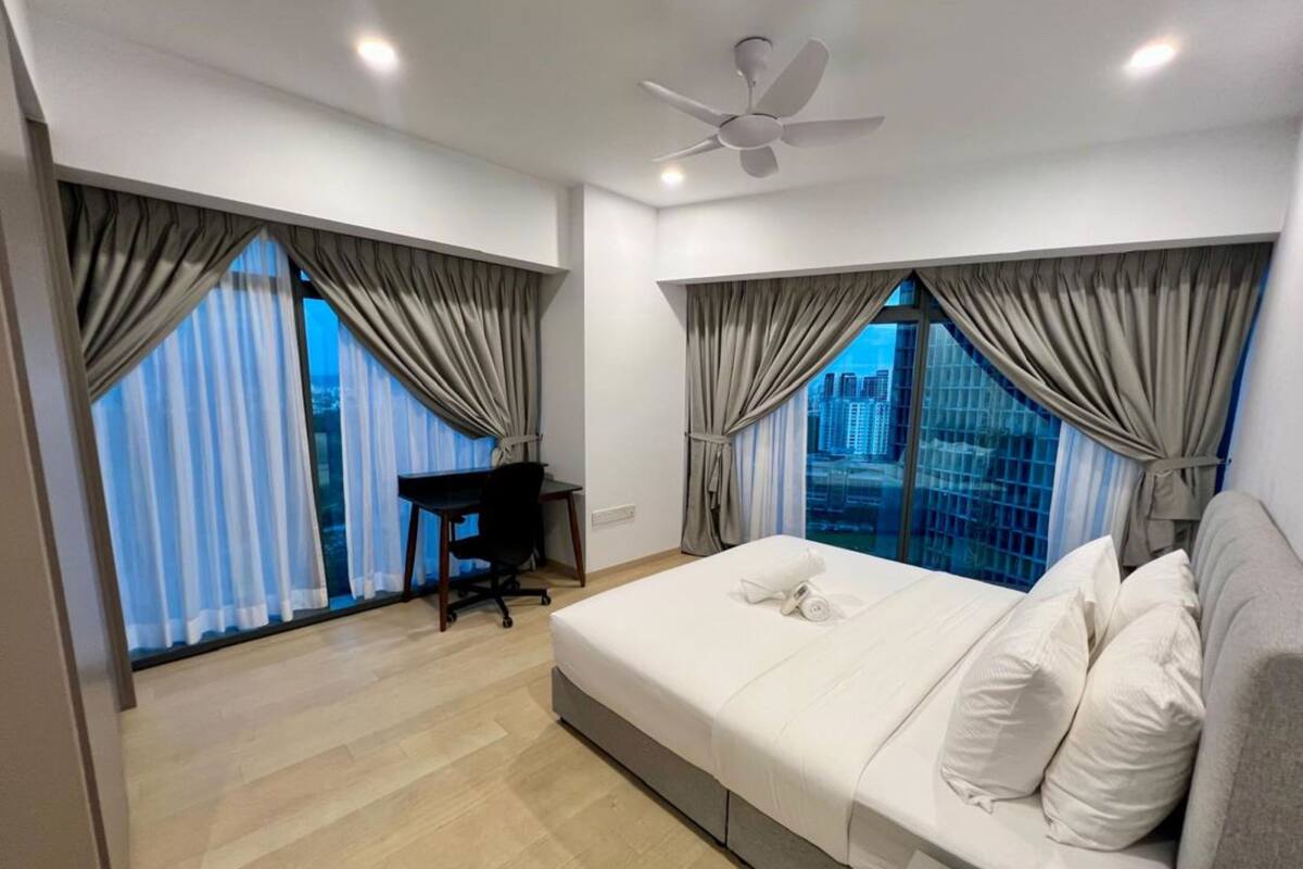 A modern hotel room with a large bed, a desk, and a view of the cityscape.