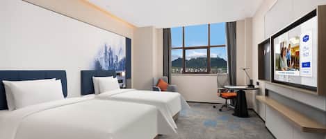 A hotel room with two beds, a desk, a chair, a TV, and a window with a mountain view.
