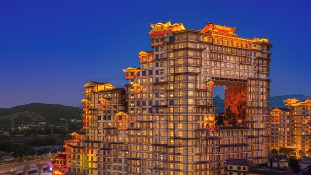 Un hotel de varios pisos con elementos arquitectónicos tradicionales, una entrada destacada y vistas del entorno.