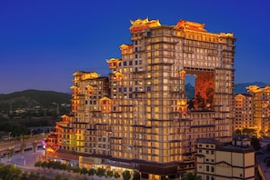 A multi-story hotel with traditional architectural elements, a prominent entrance, and a view of the surrounding area. - Hampton by Hilton Zhangjiajie (Zhangjiajie)
