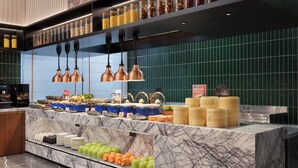 Un área de bufé con diversas opciones de comida, una encimera de mármol y lámparas colgantes.