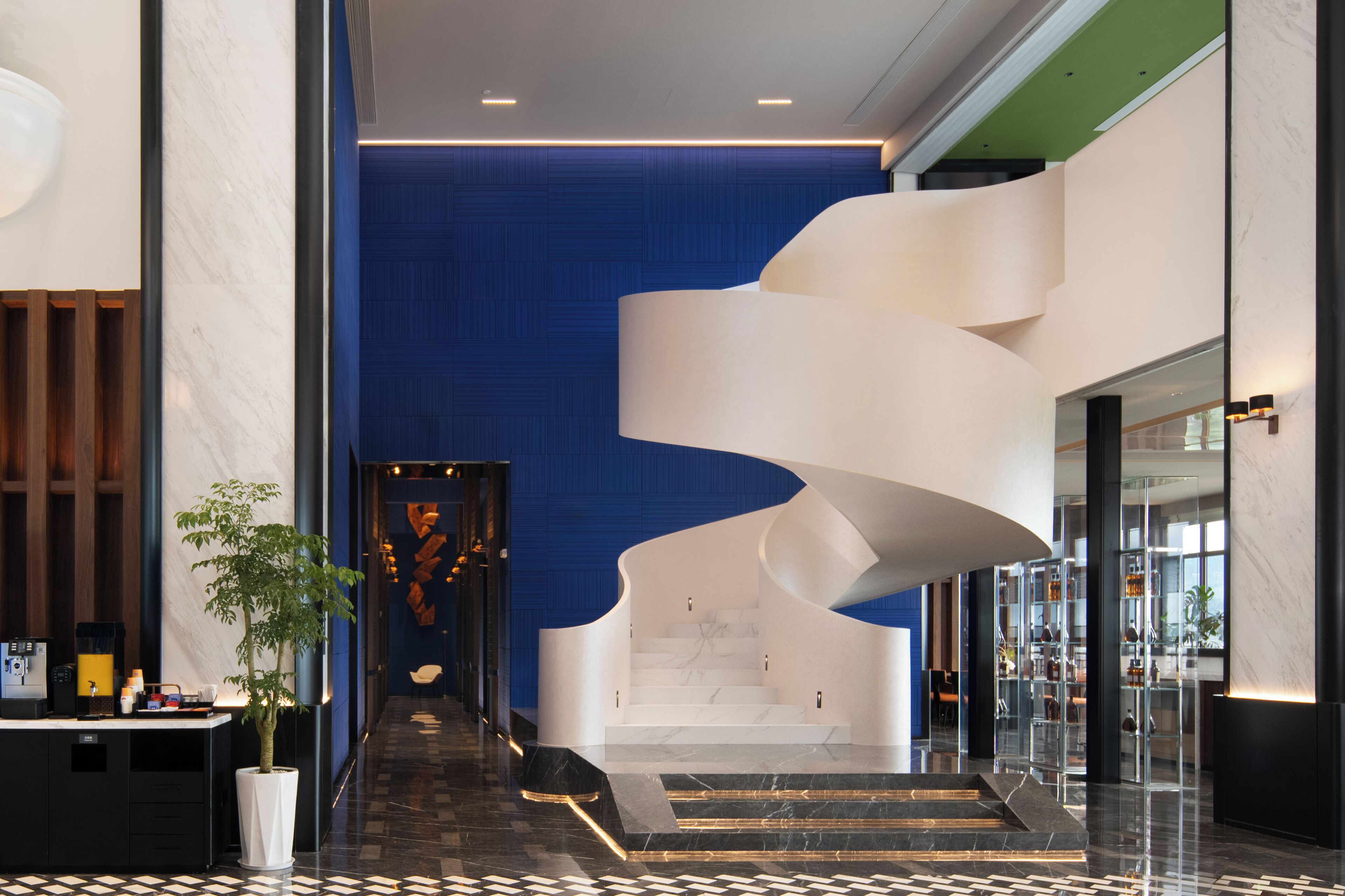 A modern lobby with a spiral staircase, marble flooring, and a checkered floor pattern.
