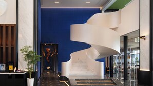 Un vestíbulo moderno con una escalera espiral, suelo de mármol y un estampado de cuadros.