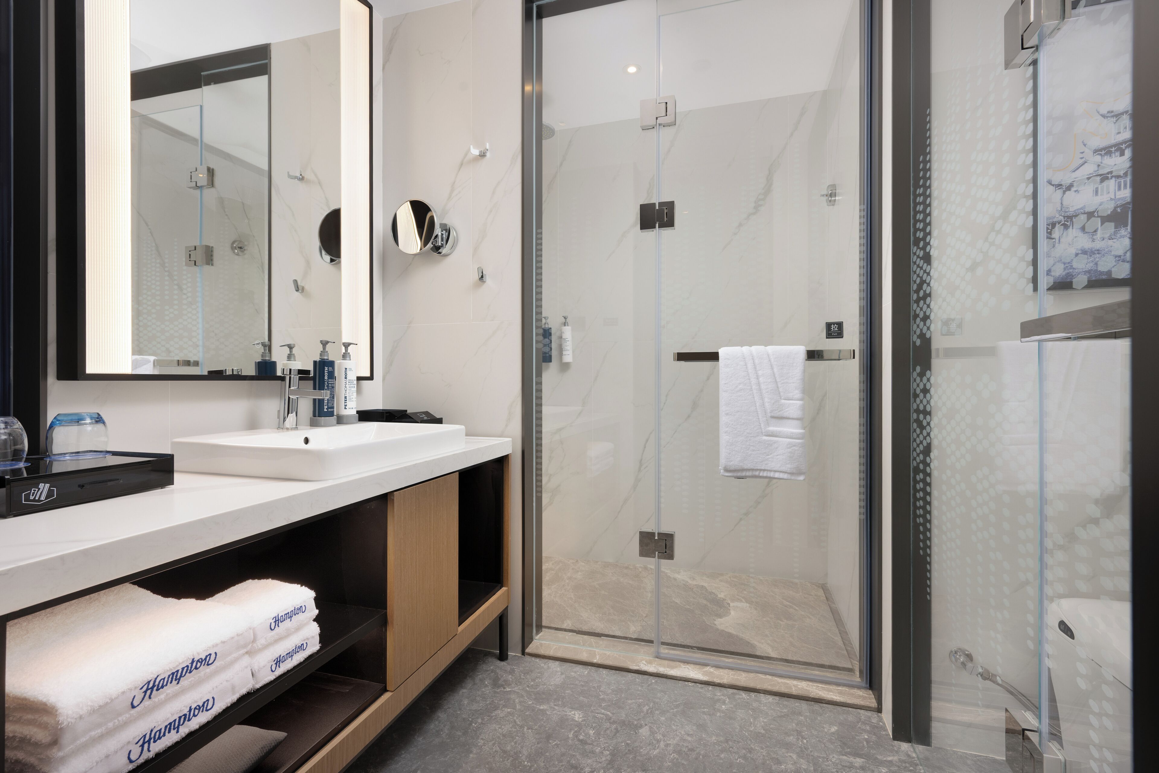 Un baño moderno con ducha envuelta en vidrio, un lavabo blanco y un espejo.