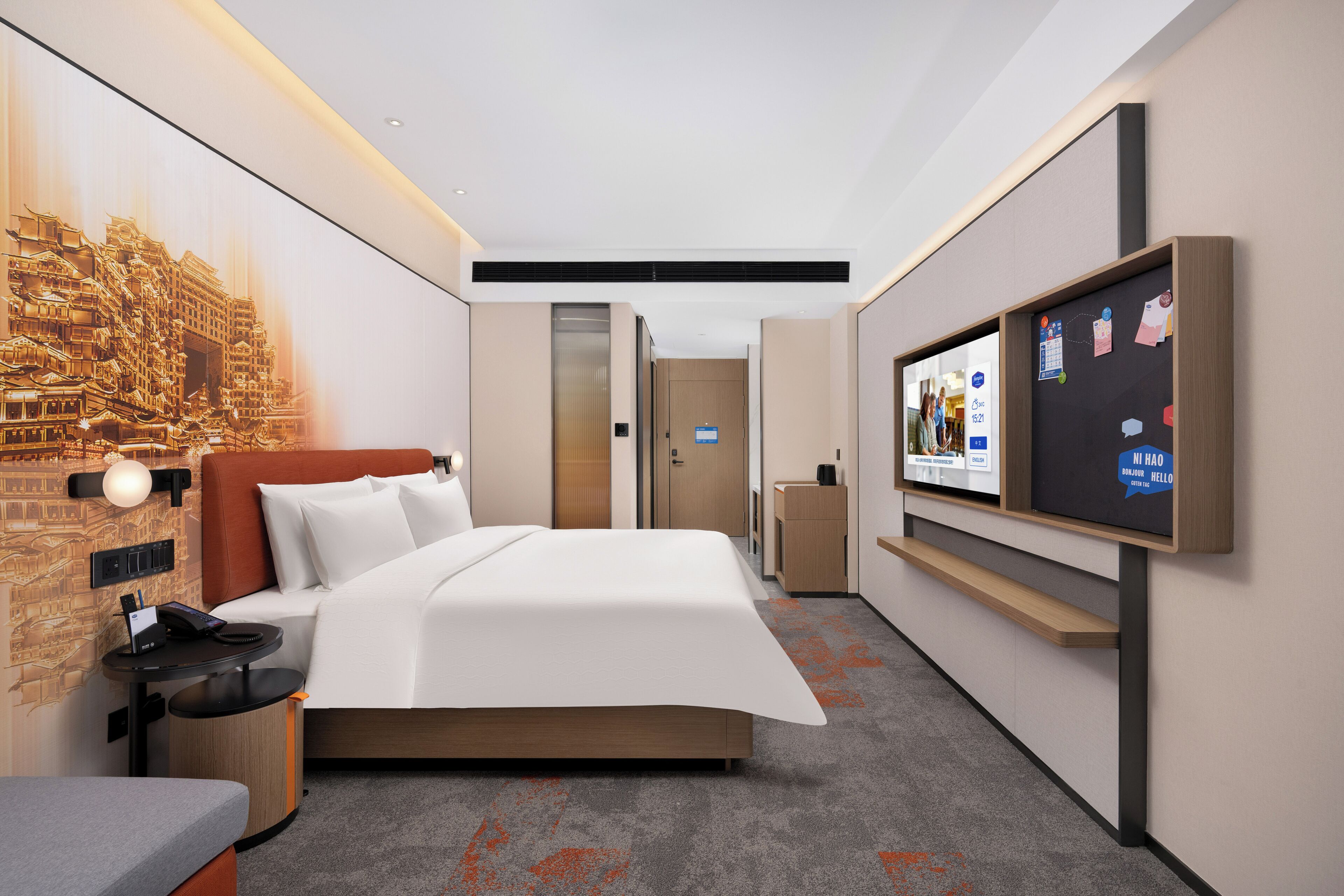 Une chambre d’hôtel équipée d’un lit, d’une télévision, d’un bureau et d’un mur orné d’une fresque.