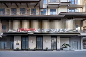 A hotel with a modern facade, a prominent sign, and a balcony with railings. - Hampton by Hilton Zhangjiajie (Zhangjiajie)
