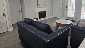 Ein Wohnzimmer mit einer Couch, Sesseln, einem Kamin und einem runden Tisch.