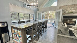 A spacious living area with a dining table, chairs, a sofa, a fireplace, and a kitchen area with a refrigerator and a coffee machine. - Upscale Mountain Retreat in Peaceful Pines! (Heber-Overgaard)