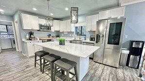 A modern kitchen with white cabinets, stainless steel appliances, and a central island with bar stools. - Upscale Mountain Retreat in Peaceful Pines! (Heber-Overgaard)