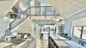 A spacious living area with a high ceiling, a staircase, a kitchen, and a dining area. - Upscale Mountain Retreat in Peaceful Pines! (Heber-Overgaard)
