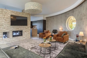 Ein modernes Wohnzimmer mit Kamin, Sofas, einem Couchtisch und einem großen Fernseher.