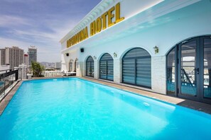 Hotel com piscina, janelas em arco grandes e um letreiro de hotel bem visível.