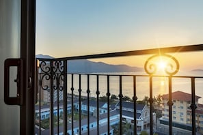 Varanda com vista para um pôr do sol sobre a água e edifícios.