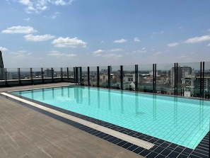 A rooftop pool with a city view, surrounded by glass railings.