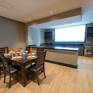 Una cocina moderna con comedor, suelo de madera y un amplio ventanal que deja entrar luz natural.