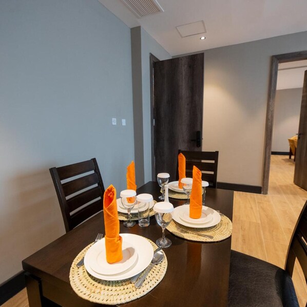 A dining area with a table set for four, including plates, cutlery, and napkins. - Sincerely Yours Suites & Serviced Apartments (Nairobi)