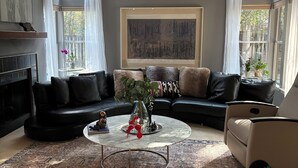 Ein Wohnzimmer mit einem schwarzen Ledersofa, einem runden Couchtisch, einer Holzbank und einem Deckenventilator.