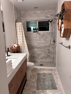 Une salle de bain équipée d’une douche, de toilettes et d’un meuble-lavabo avec un plan de travail en marbre.