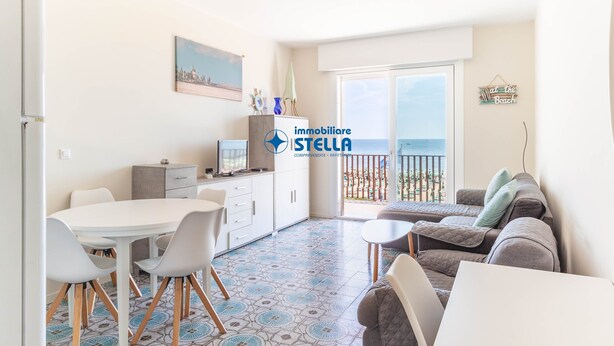 En moderne lejlighed med spiseplads, tekøkken og en balkon med havudsigt.