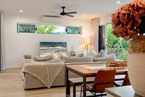 A modern living room with a sofa, a coffee table, and a dining area.