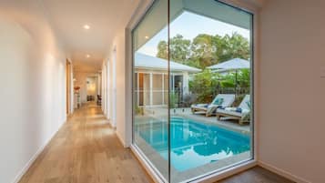 A modern interior with a glass wall leading to an outdoor pool area.