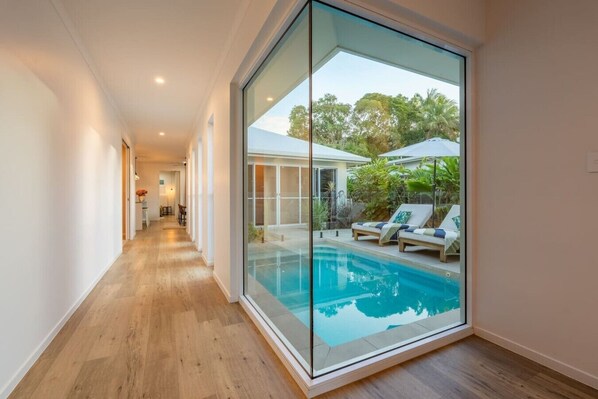 A modern interior with a glass wall leading to an outdoor pool area.