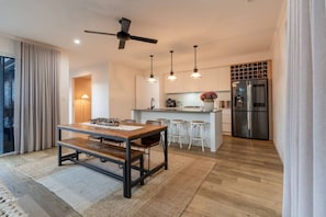 A modern kitchen with a central island, bar stools, a ceiling fan, pendant lights, and a built-in wine rack.