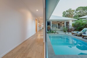 Een modern huis met zwembad, houten vloeren en uitzicht op de achtertuin.