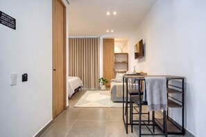 Una habitación de hotel moderna con cama, escritorio, televisor y un pequeño rincón de descanso.
