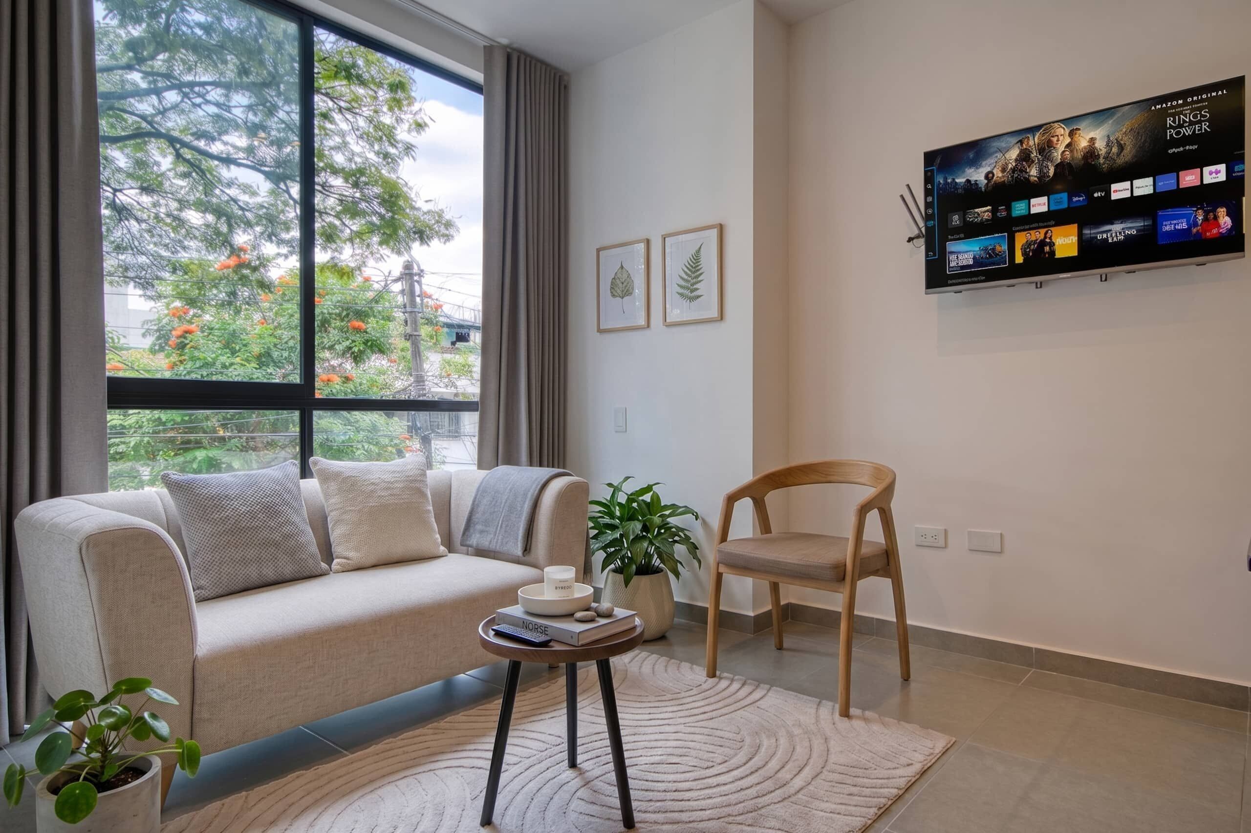 Una sala de estar moderna con un sofá, un sillón, una mesa de centro y un televisor de pantalla plana montado en la pared.