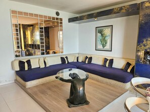 Ein modernes Wohnzimmer mit einem Ecksofa, einem Couchtisch, einer dekorativen Skulptur und einem großen Spiegel.