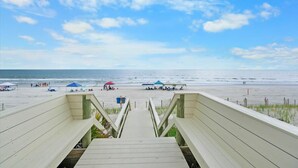 A wooden staircase leading to a beach with umbrellas and people. - Oceanfront 3BR Condo in St. Augustine (St. Augustine)