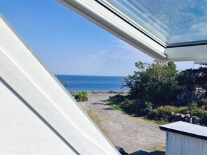 Blick durch ein Fenster auf einen klaren Himmel und das Meer in der Ferne.