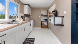 Eine moderne Küche mit weißen Schränken, einer Holz Arbeitsplatte, einem eingebauten Backofen und einer Mikrowelle.