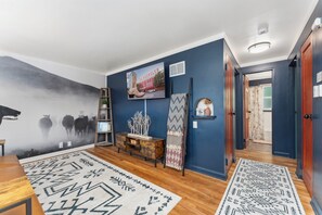 A living room with a blue wall, a wooden floor, a mounted TV, and a patterned rug.