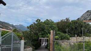 Un camino que lleva a una casa con un muro de piedra y una verja de metal.