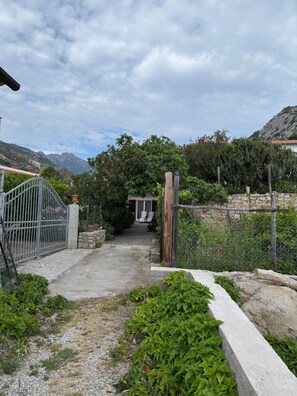 Un camino que lleva a una casa con un muro de piedra y una verja de metal.