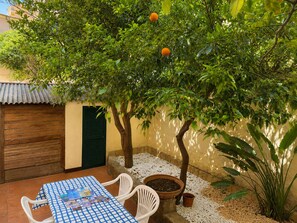 Een terras met een tafel en stoelen, omgeven door een tuin met een fruitboom.
