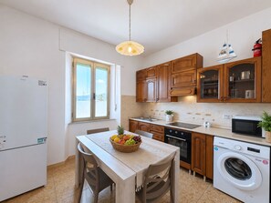 A compact kitchen with wooden cabinets, a built-in oven, a microwave, and a washing machine. - Le Finestre sul Porto (Portoferraio)