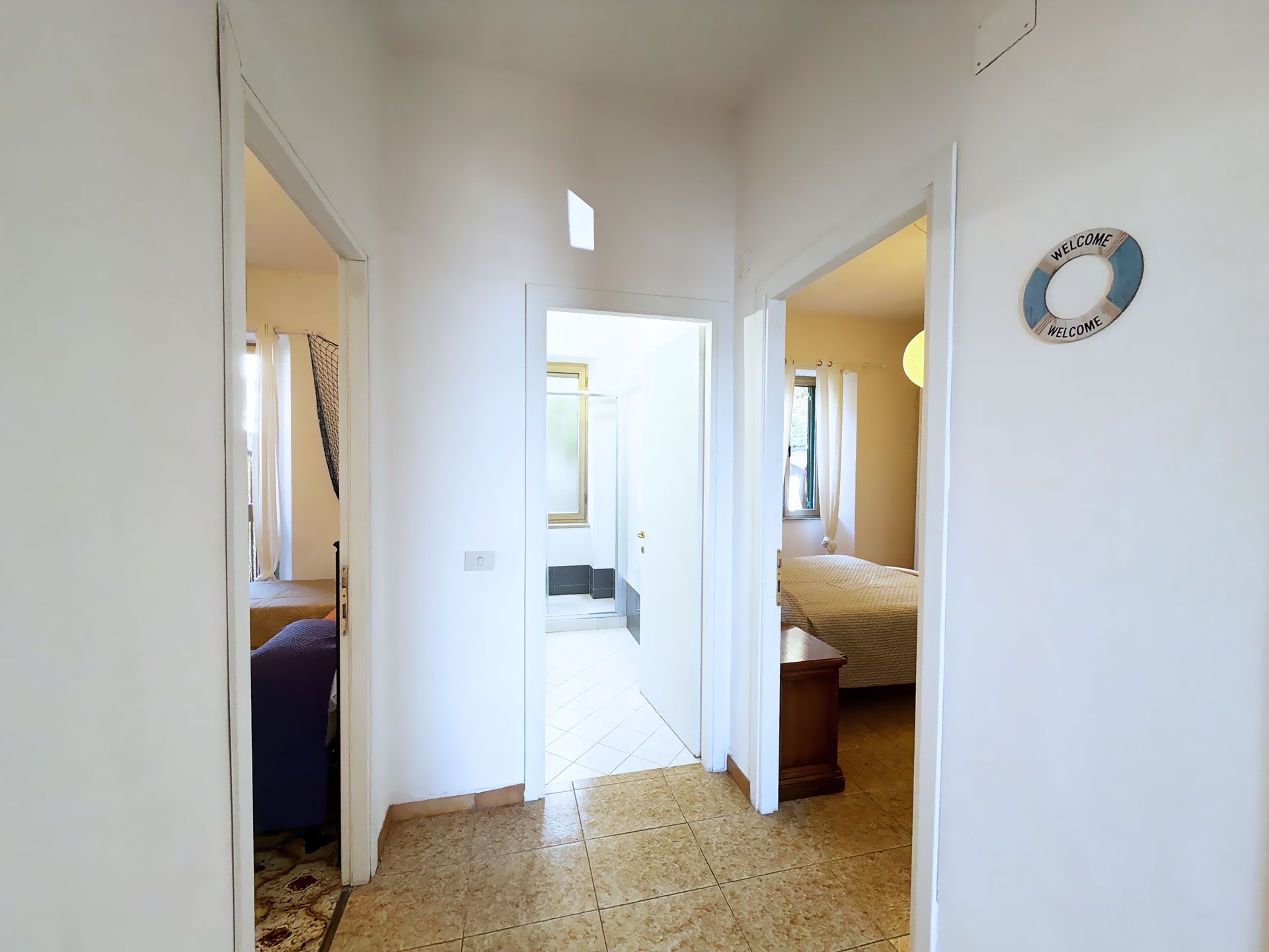 Un pasillo que conduce a un dormitorio con una cama y una mesita de noche.
