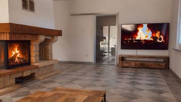 Ein Wohnzimmer mit Kamin, Fernseher und einer Couch.